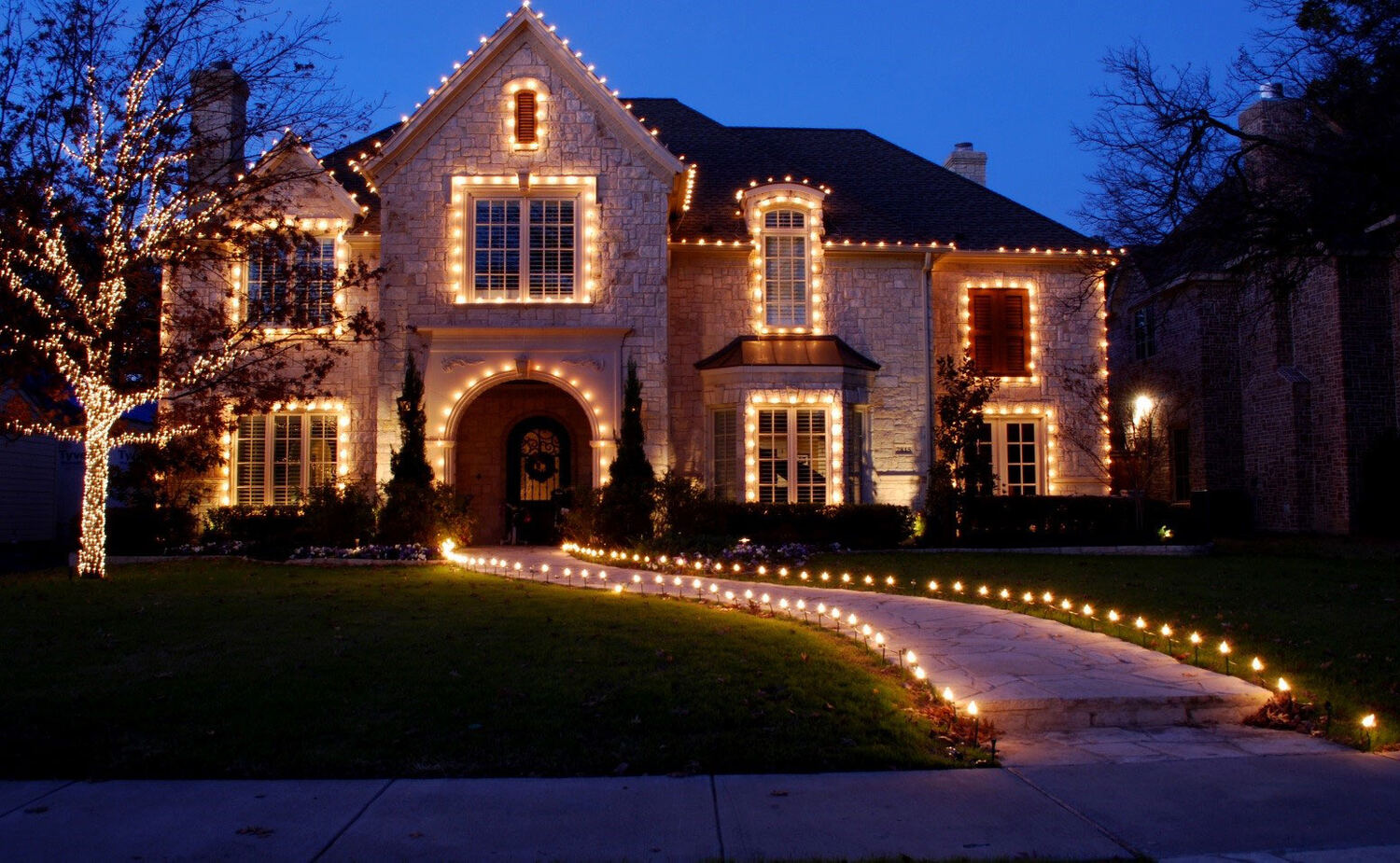 Estate with lit trees and a glowing curved pathway